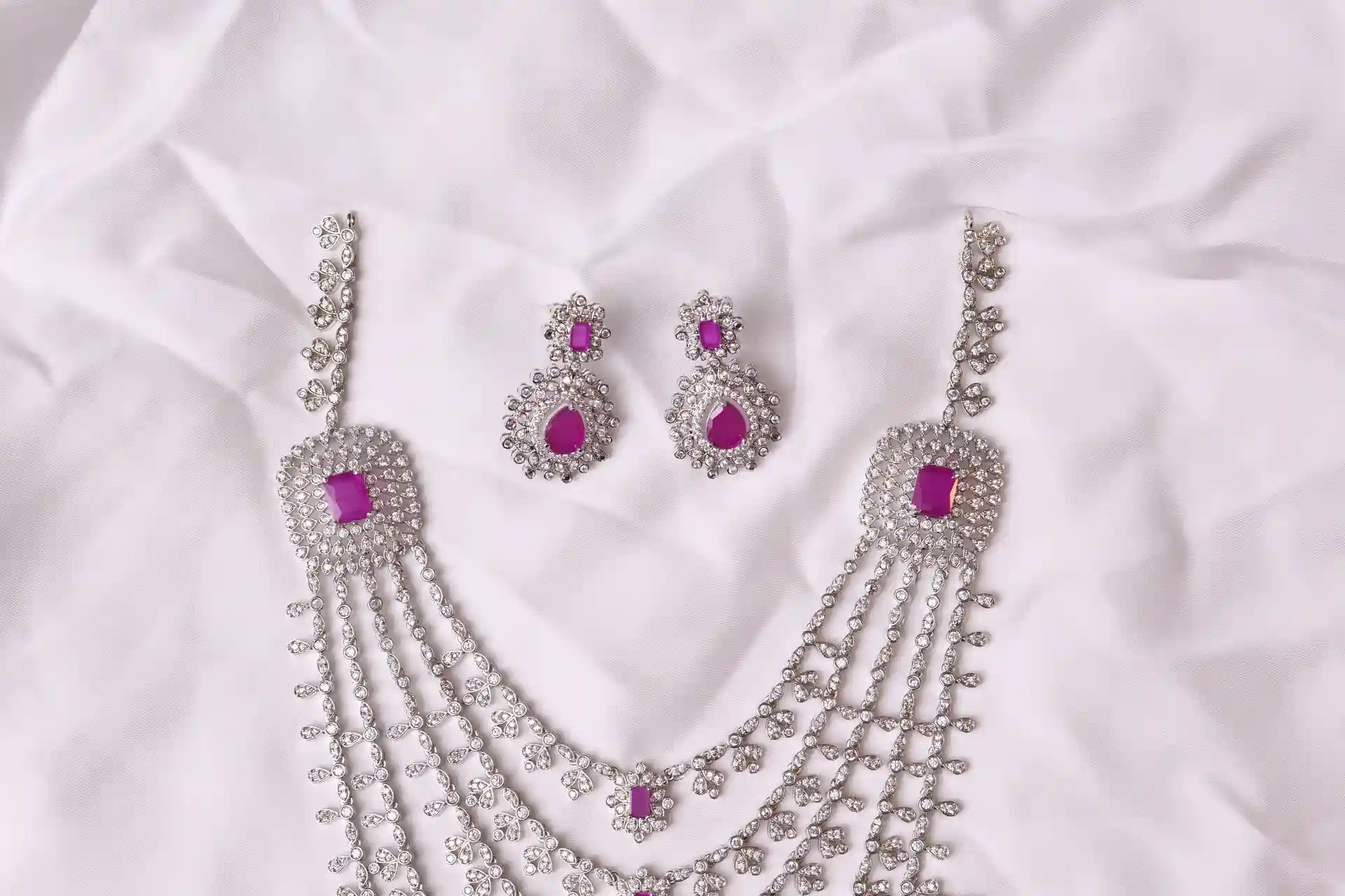 Close-up of Tess Long Mala Necklace Leaf-Link Chain and Matching Ruby-Pink CZ Earrings