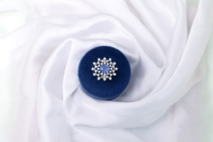 Natural oval sapphire halo ring in 925 stamped silver with starburst accent stones, shown in a navy velvet ring box