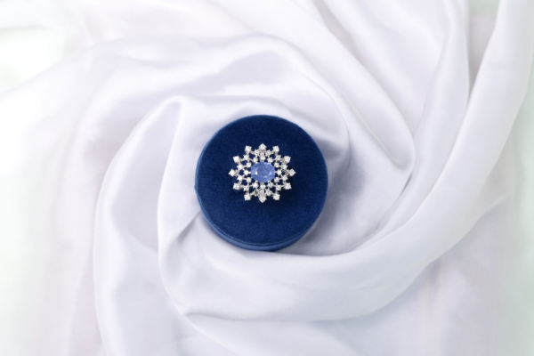 Natural oval sapphire halo ring in 925 stamped silver with starburst accent stones, shown in a navy velvet ring box